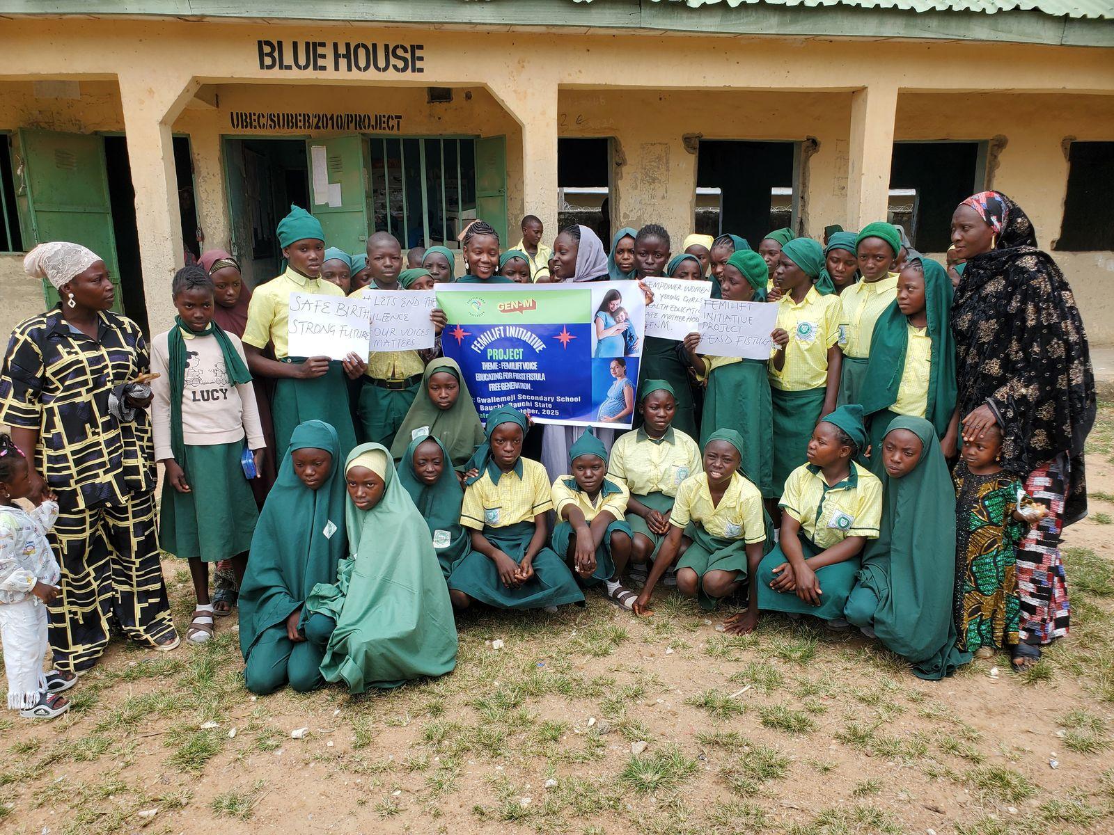 Schoolgirls and their teachers gather outdoors with FCI volunteers and a fistula education banner