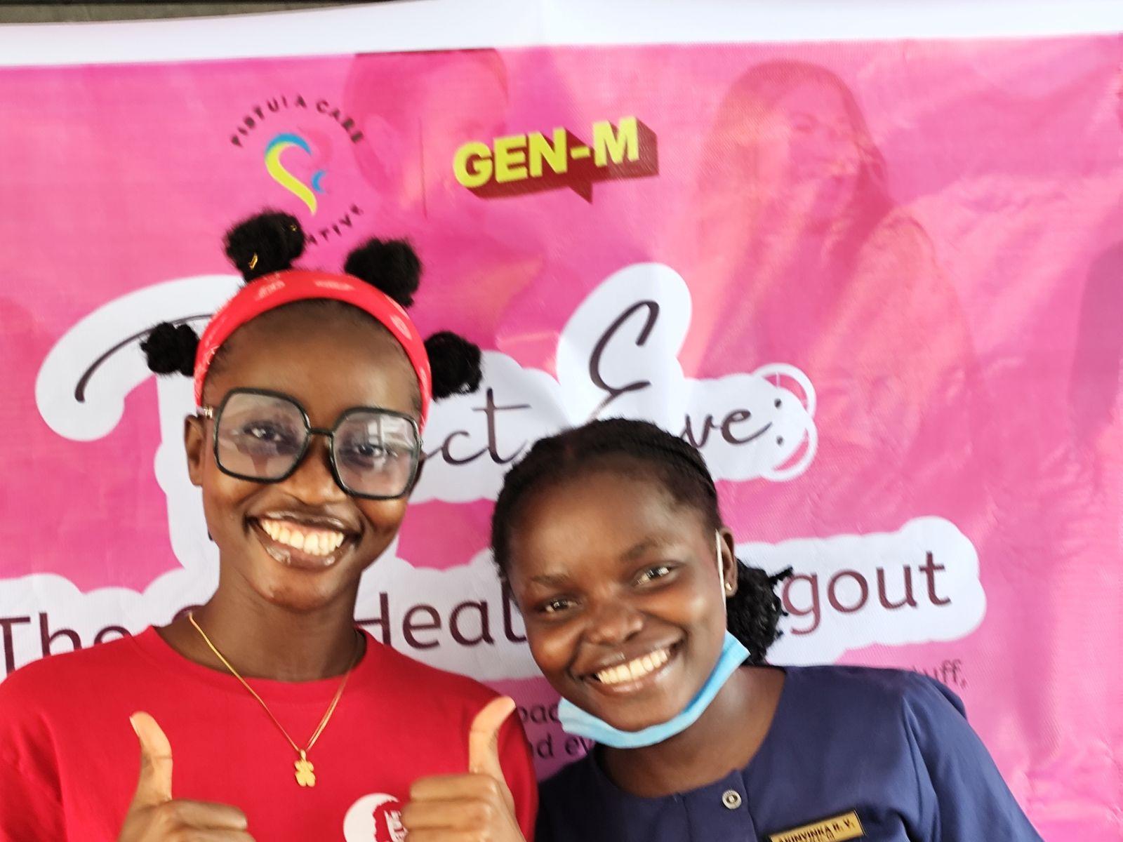 Two smiling young women give a thumbs up in front of a Project Eve banner